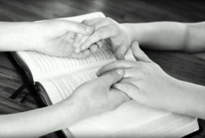 Hands held over open Bible
