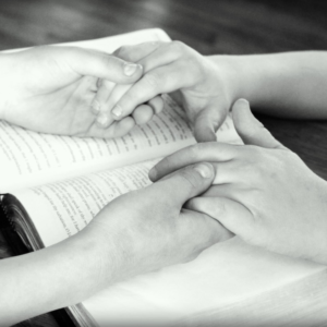 Hands held over open Bible
