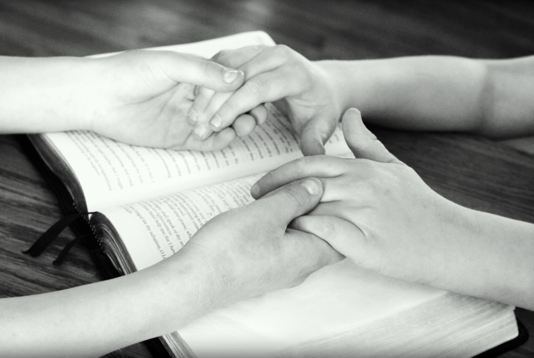 Hands held over open Bible