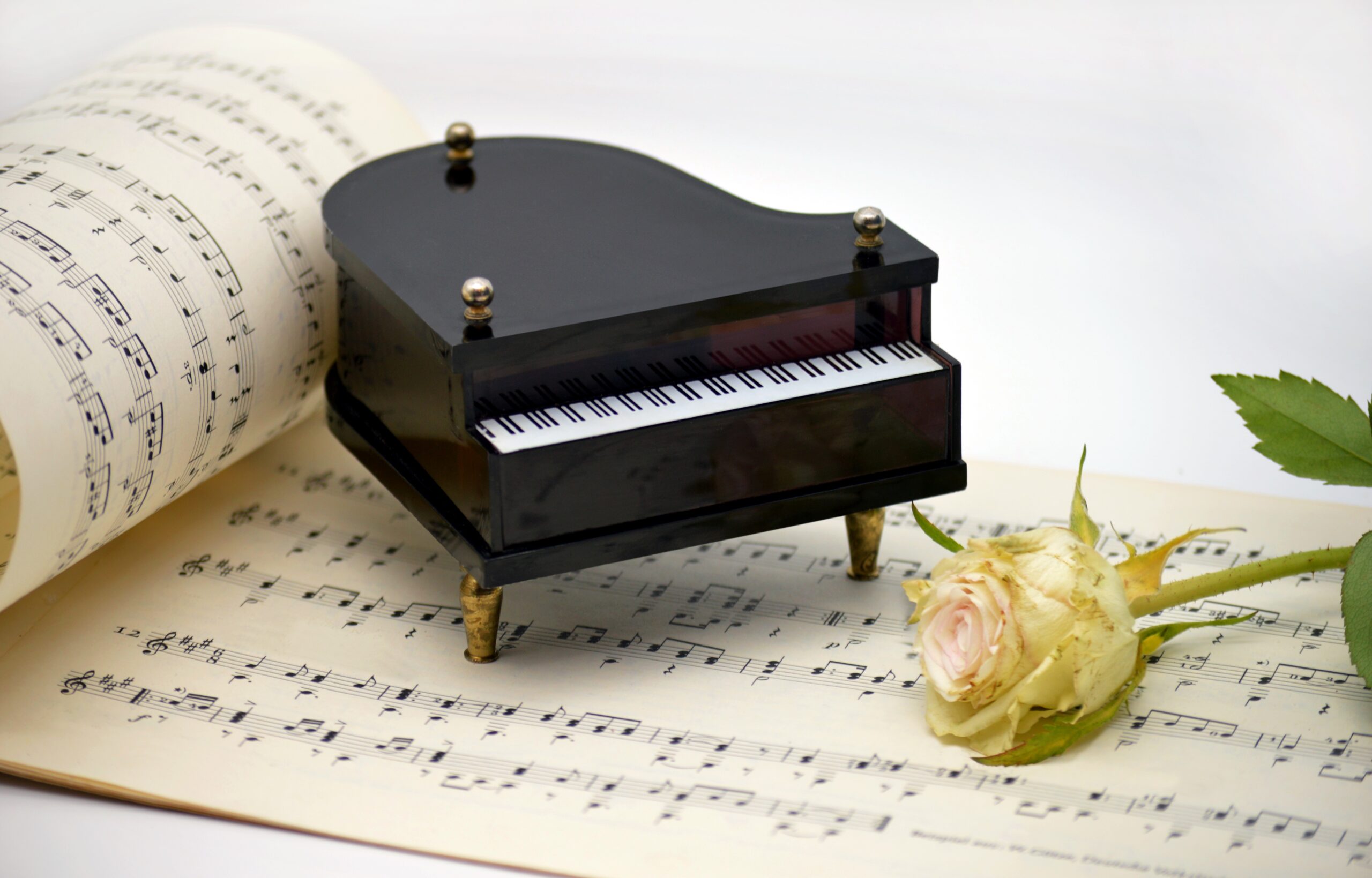Image of piano sculpture and a rose on sheet music
